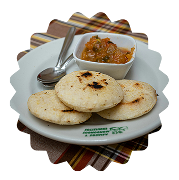 shows a picture of one of the most famous quick meals in Colombia called Arepas. The picture features 3 Arepas in a plate with some salsa on the sie of the plate 